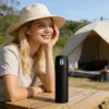 A girl using the Gencore black travel tumbler at an outdoor campsite, highlighting portability and outdoor durability.