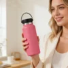 Lifestyle photography of a woman holding a pink 32oz wide mouth insulated bottle in a modern interior setting.